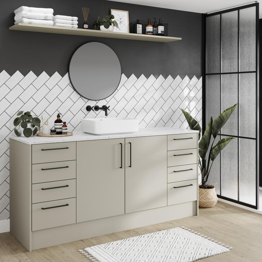 Slab bathroom with sandstone cupboard doors. Has a white worktop, tiles, oak floors, and black handles for a modern touch.