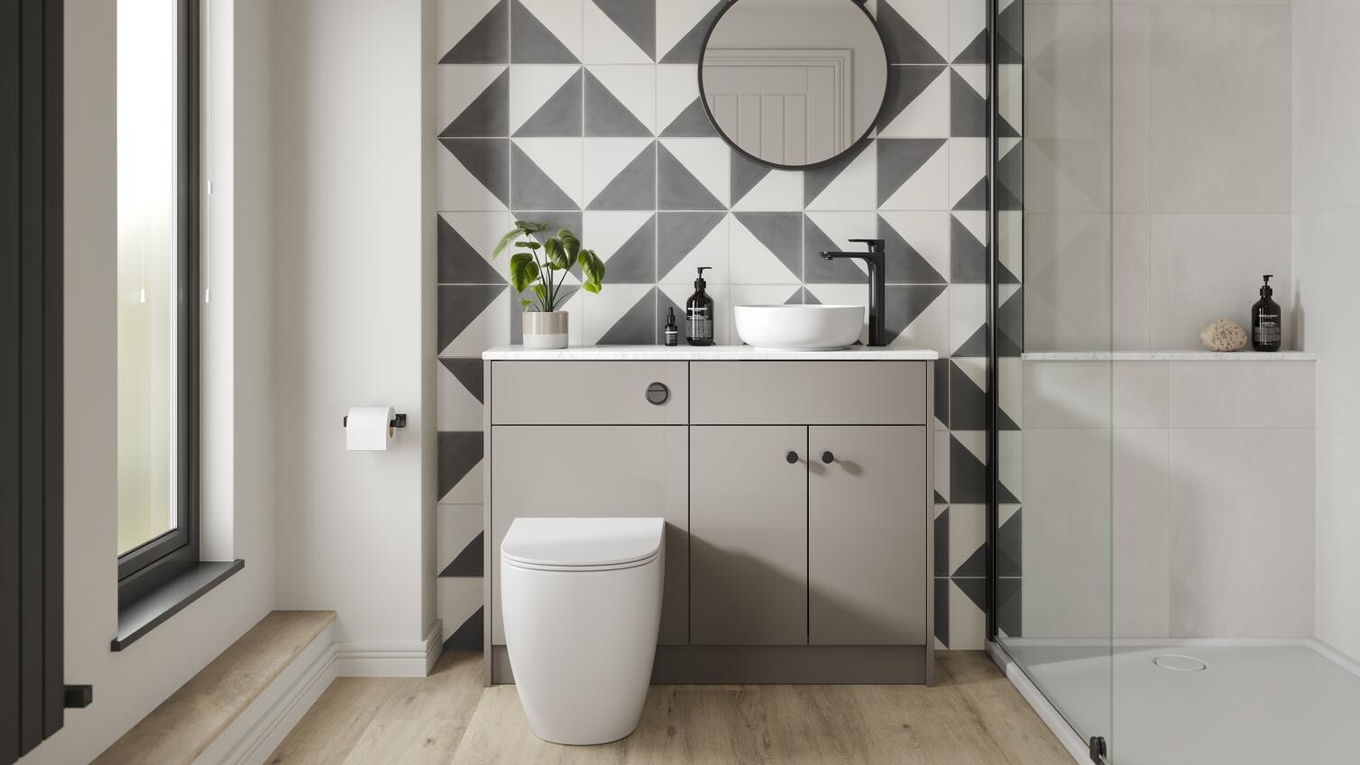A gloss, sand grey bathroom with black fittings. There is a floor-to-ceiling glass shower enclosure and oak flooring. 