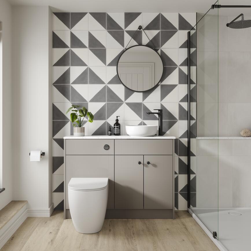 A gloss, sand grey bathroom with black fittings. There is a floor-to-ceiling glass shower enclosure and oak flooring. 