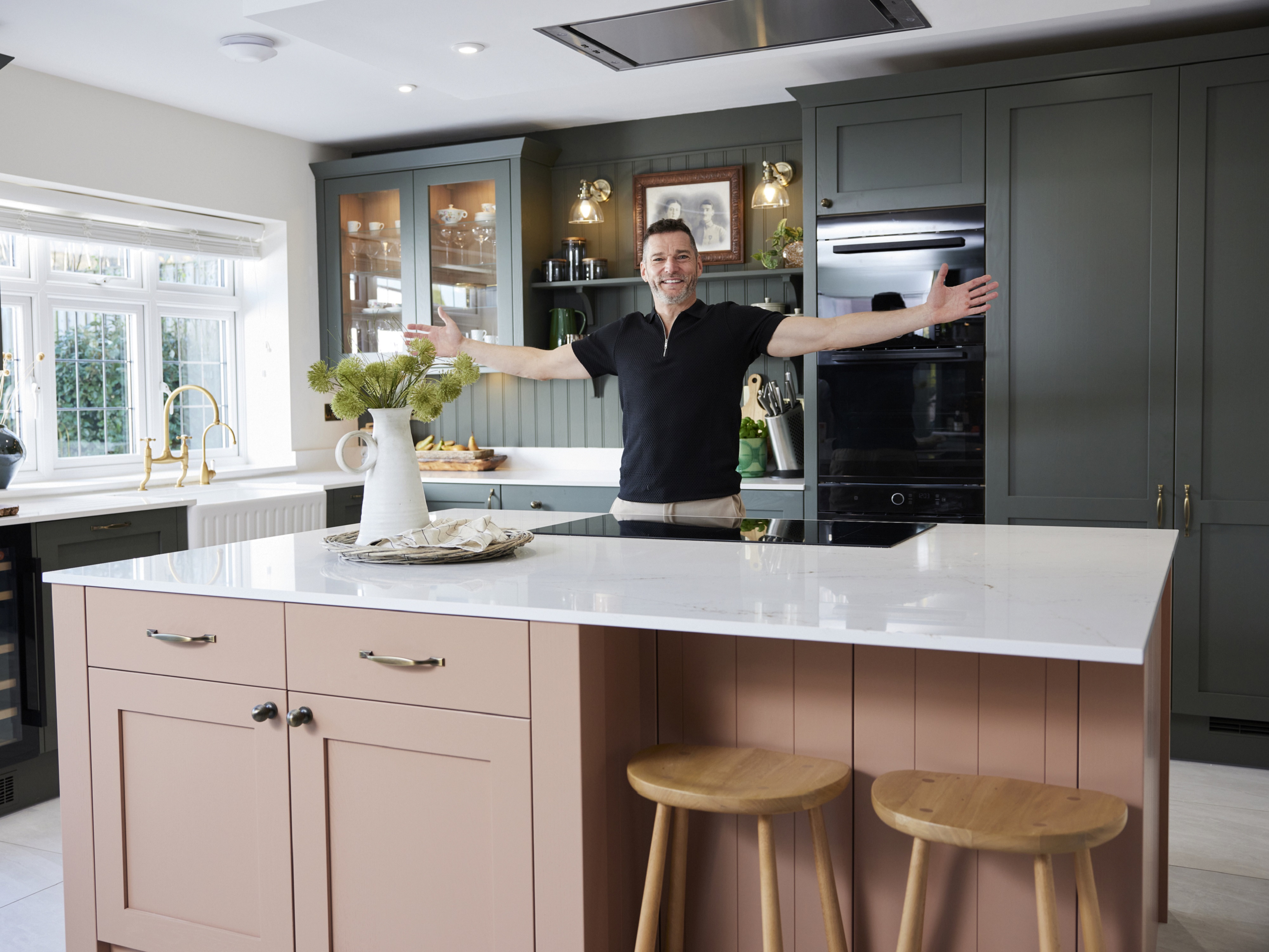 Fred stood with his arms aloft in his new green and orange Howdens kitchen