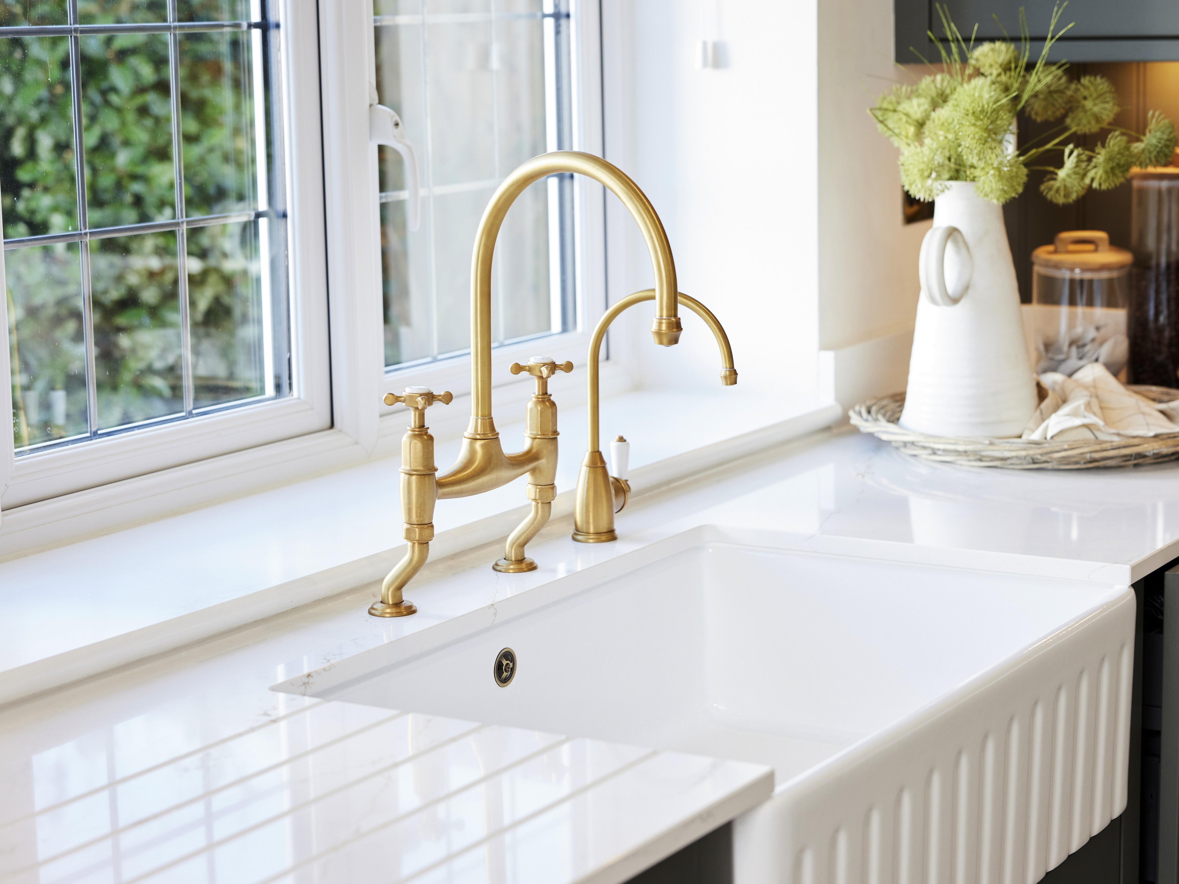 A golden bridge tap finished in an aged bronze, set into a white worktop