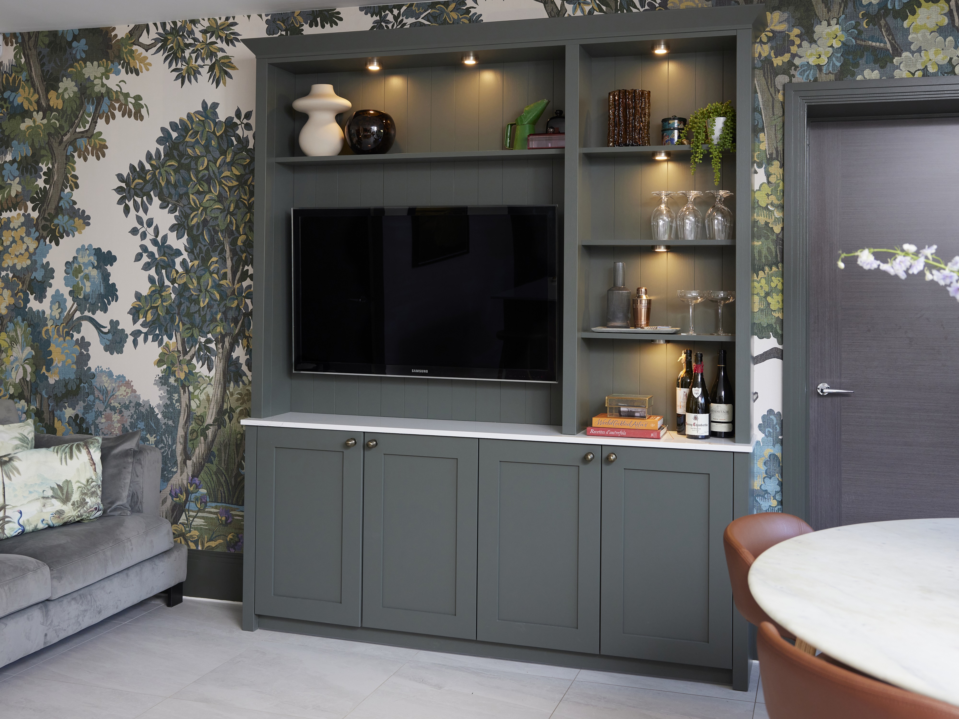 A sideboard made using ash green chilcomb cabinets, with a TV and cocktail making equipment