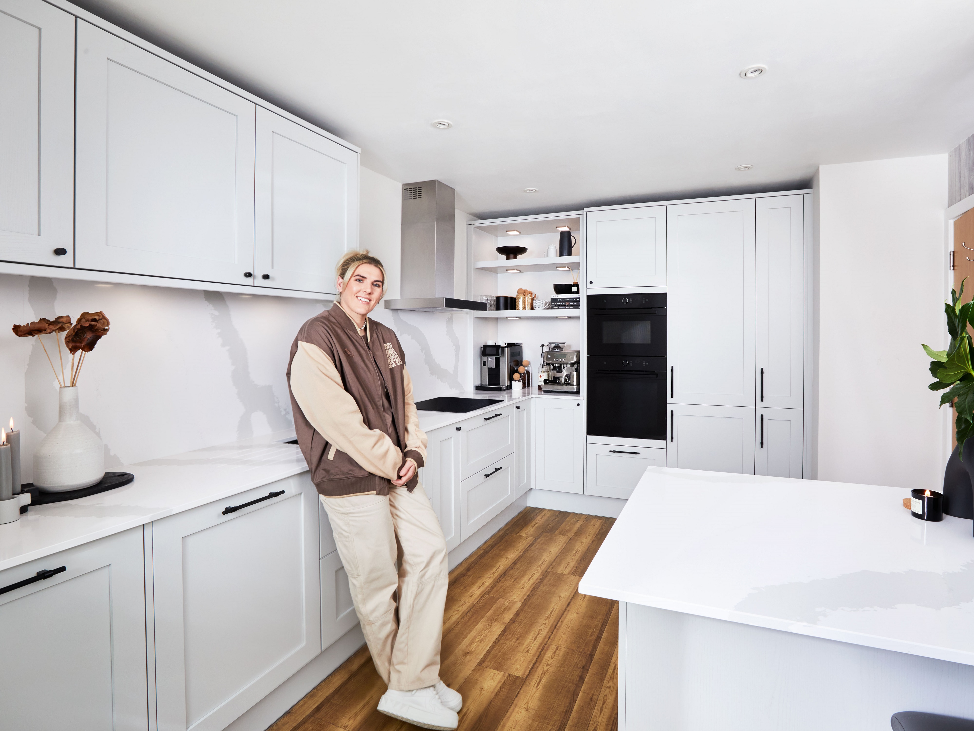 Millie Bright leaning against a counter in her new, white kitchen