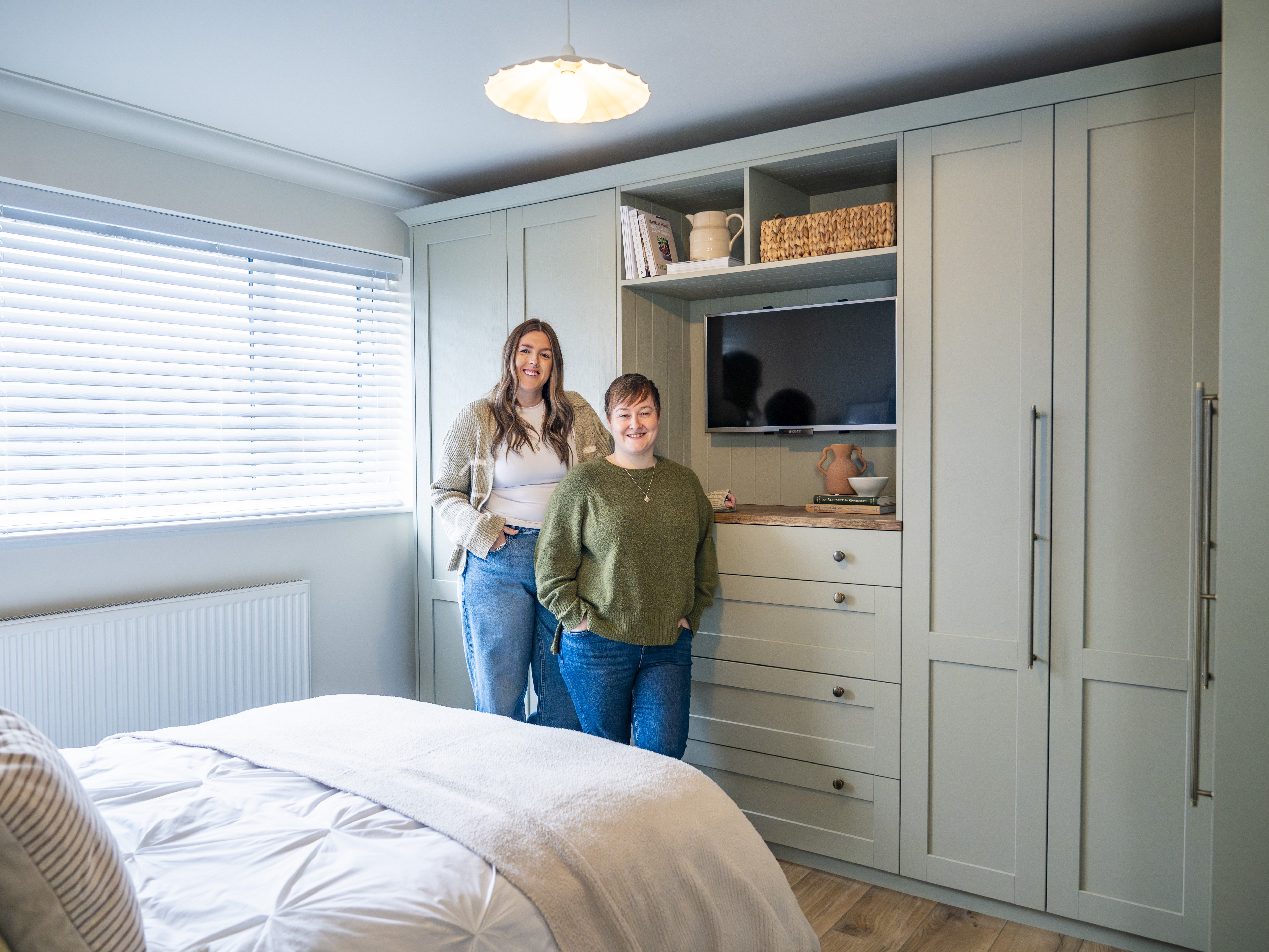 Two women posing in front of their new bedroom units