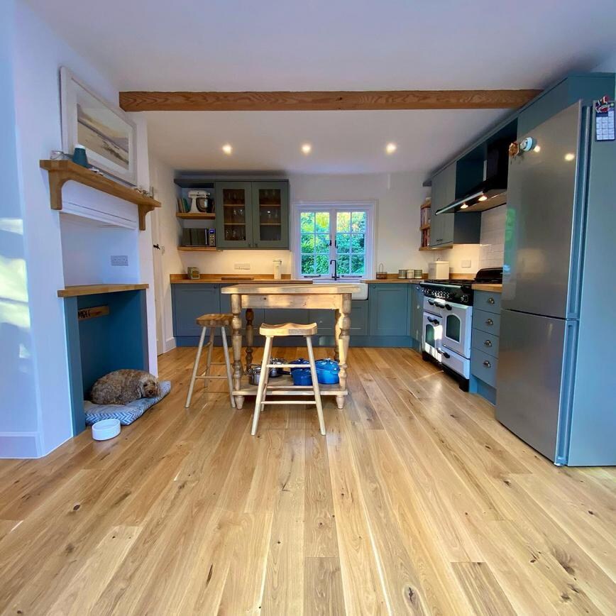 Sage green shaker kitchen idea with an l-shaped layout, a farmhouse style kitchen island with wooden stalls and oak floors.