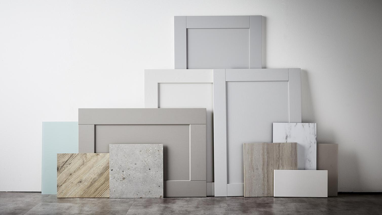 Calm haven flat lay showing a textured stone slab, light oak panels and shaker door fronts in tonal grey shades..