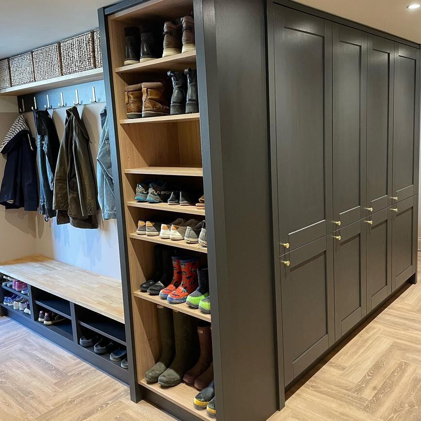Small boot room idead with tower units in black. Features open shelving and herringbone flooring.