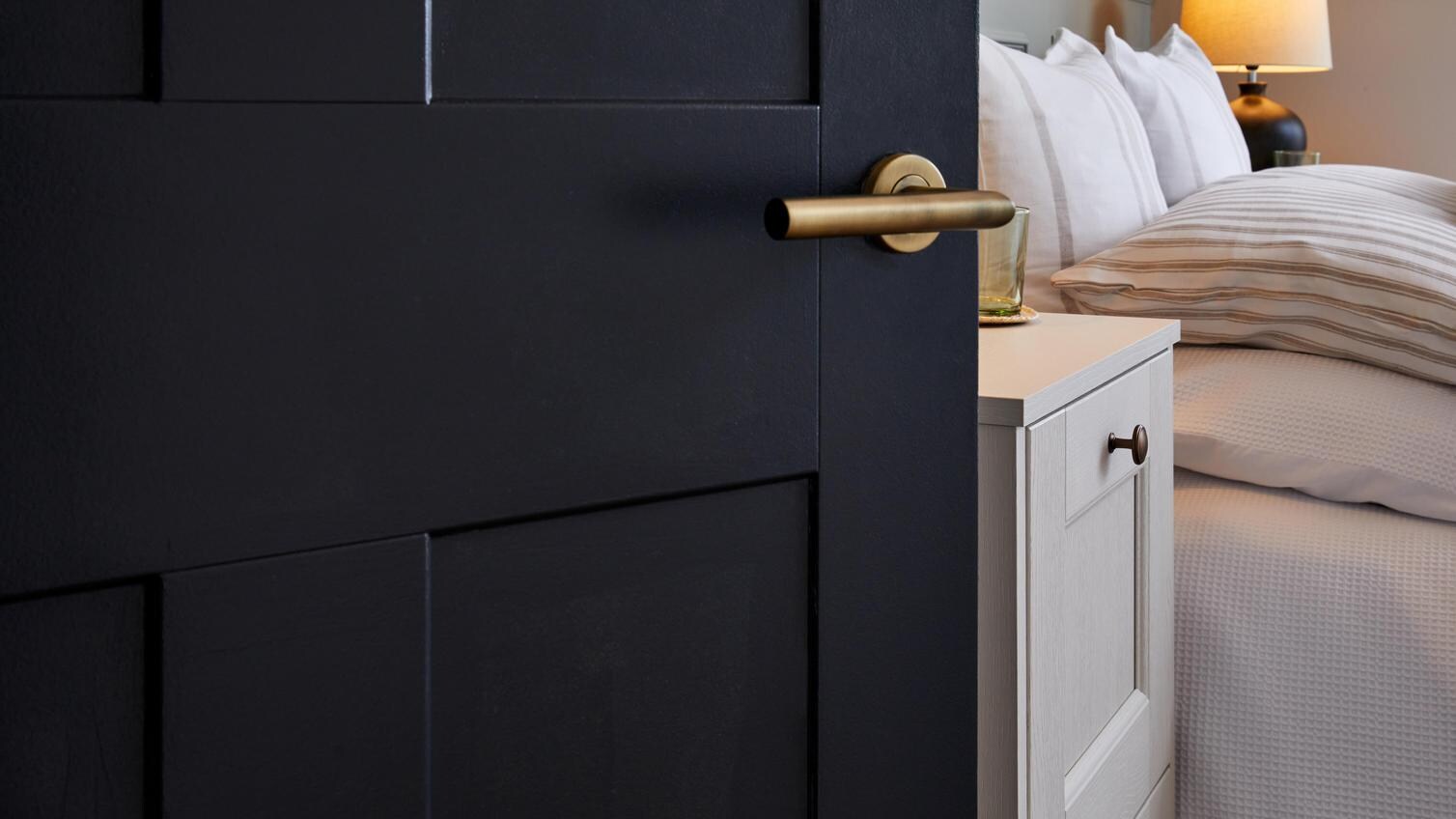 A Burford, panelled internal door to the bedroom. It has been painted in a navy finish & completed with brushed brass handles
