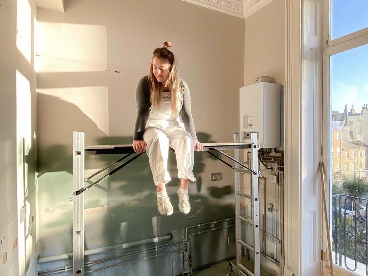 Poppy sitting on scaffolding in a room with green paint on walls.