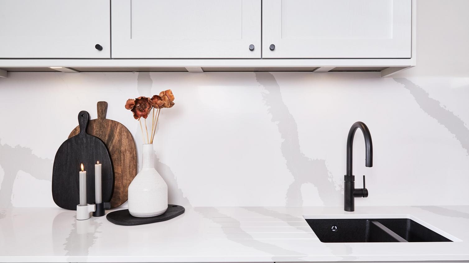 A dove-grey kitchen featuring white, quartz worktops and backboards with a marble-effect pattern for a luxurious look.