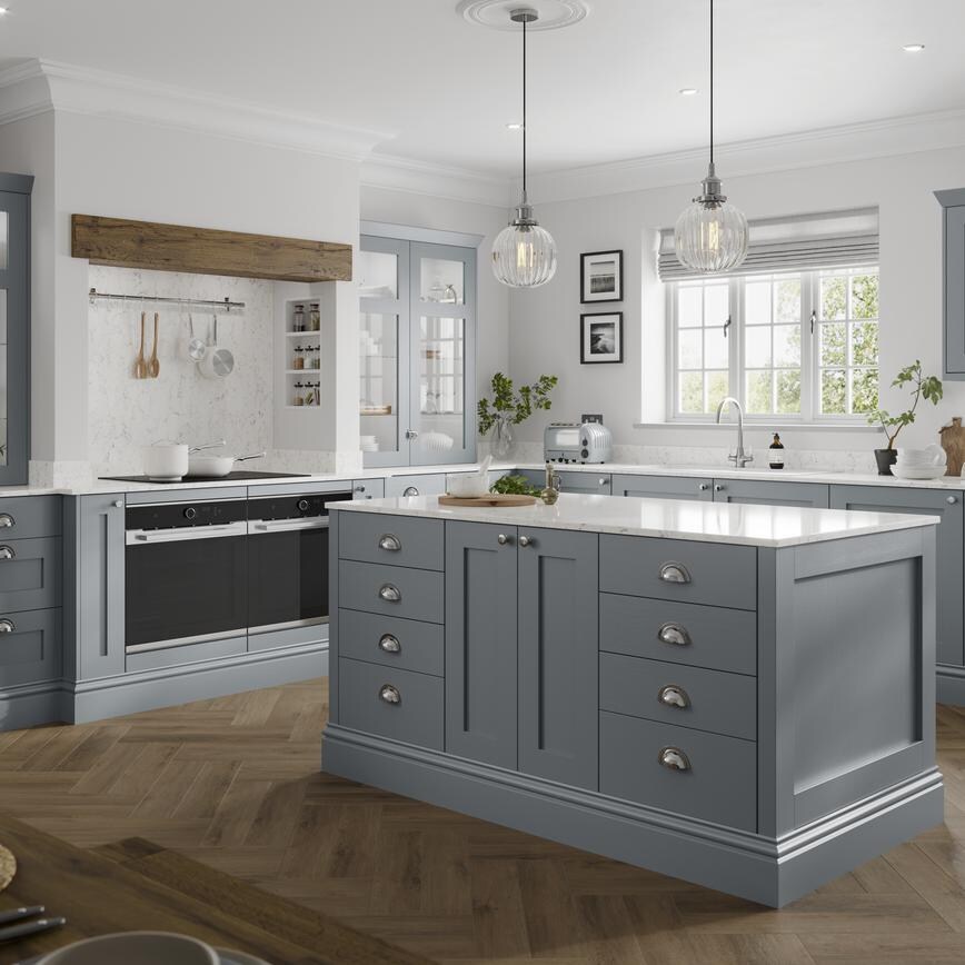 A blue shaker kitchen idea in an L-shaped layout with island. Includes white worktops, glass cabinets, and chrome handles.