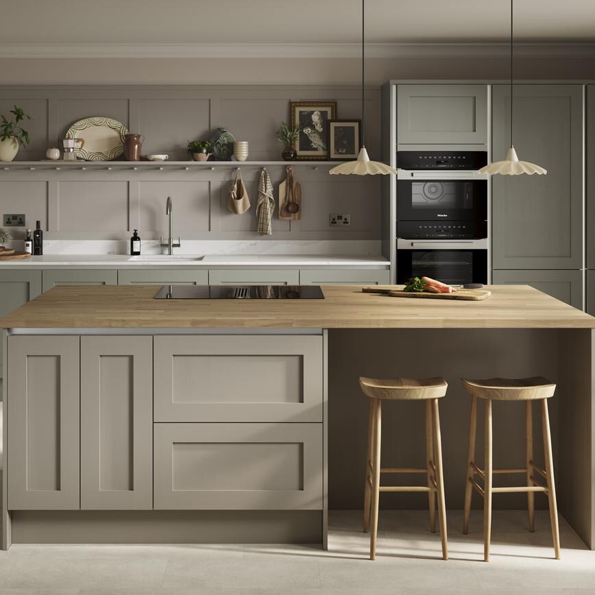 A green shaker kitchen with silver profiles for a handleless design. Has oak worktops and stone floors for a natural look.