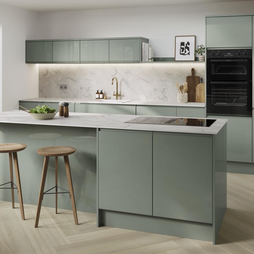 Gloss green kitchen with an island in the centre of the room. There are white marble-effect worktops and herringbone flooring