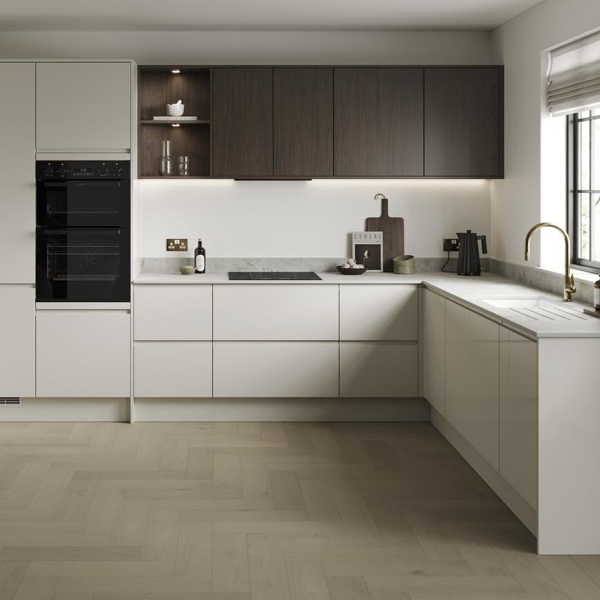 An l-shaped kitchen layout in a white porcelain colour. It has light oak herringbone flooring an integrated appliances.