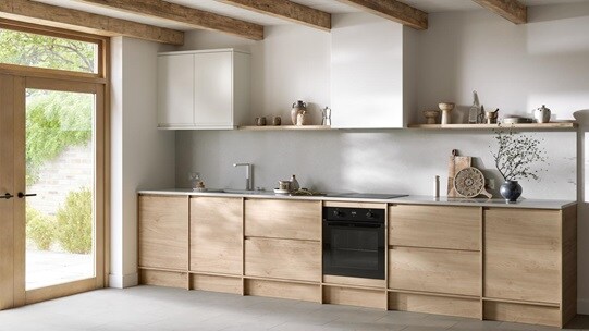 Natural oak kitchen from the Clerkenwell collection. It is in a single-wall layout with tiled flooring & white wall cabinets.