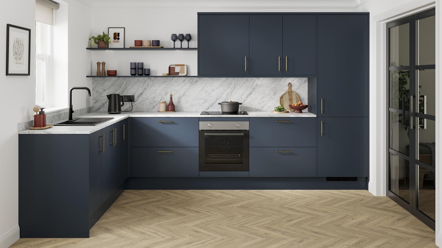 A marine blue kitchen with slab doors and brass handles. It is in an l-shaped layout, with grey worktop and oak flooring.