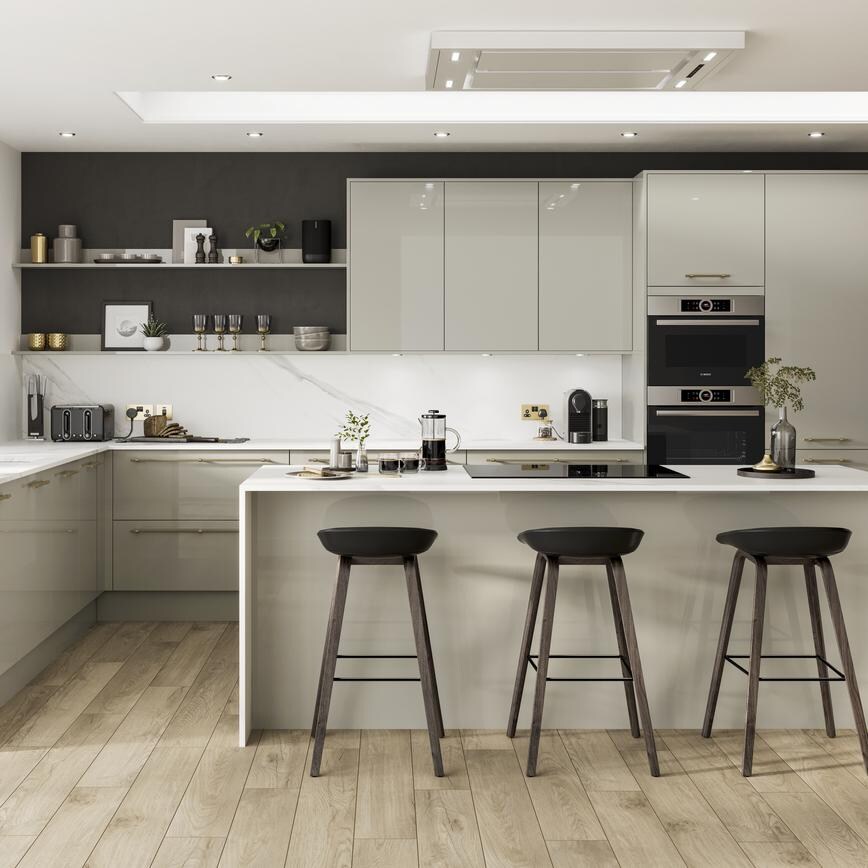 Contemporary kitchen in an island layout with neutral slab doors in a glossy finish. Contains white worktops and a black tap.