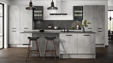 Grey kitchen in an island layout with concrete cupboard doors in a slab design. Includes black bar handles and glazed units.