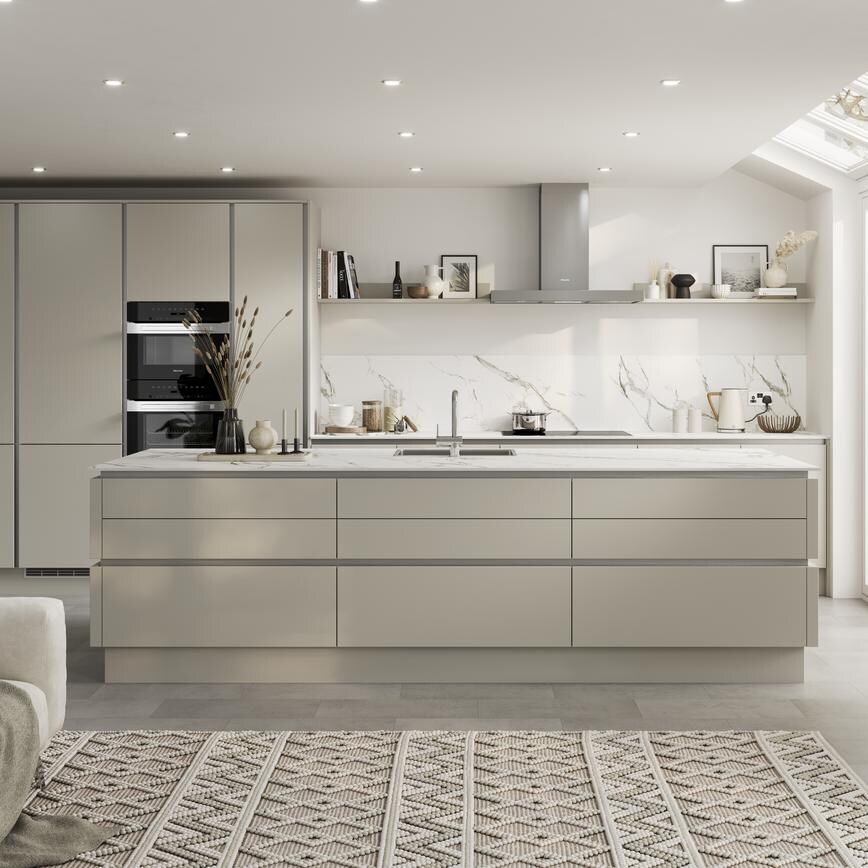 Neutral slab doors with a super-matt finish in an island layout. Has handleless units and silver trims for a modern look.