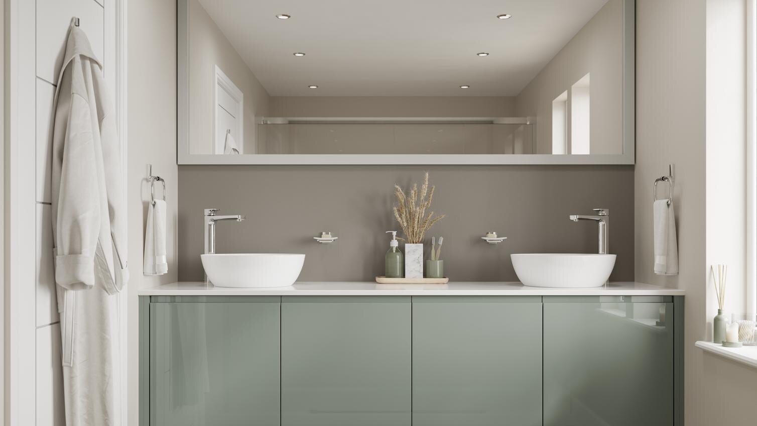 A green gloss bathroom, with slab fronts and integrated handles. It is finished with a white worktop, wall mirror, and sinks