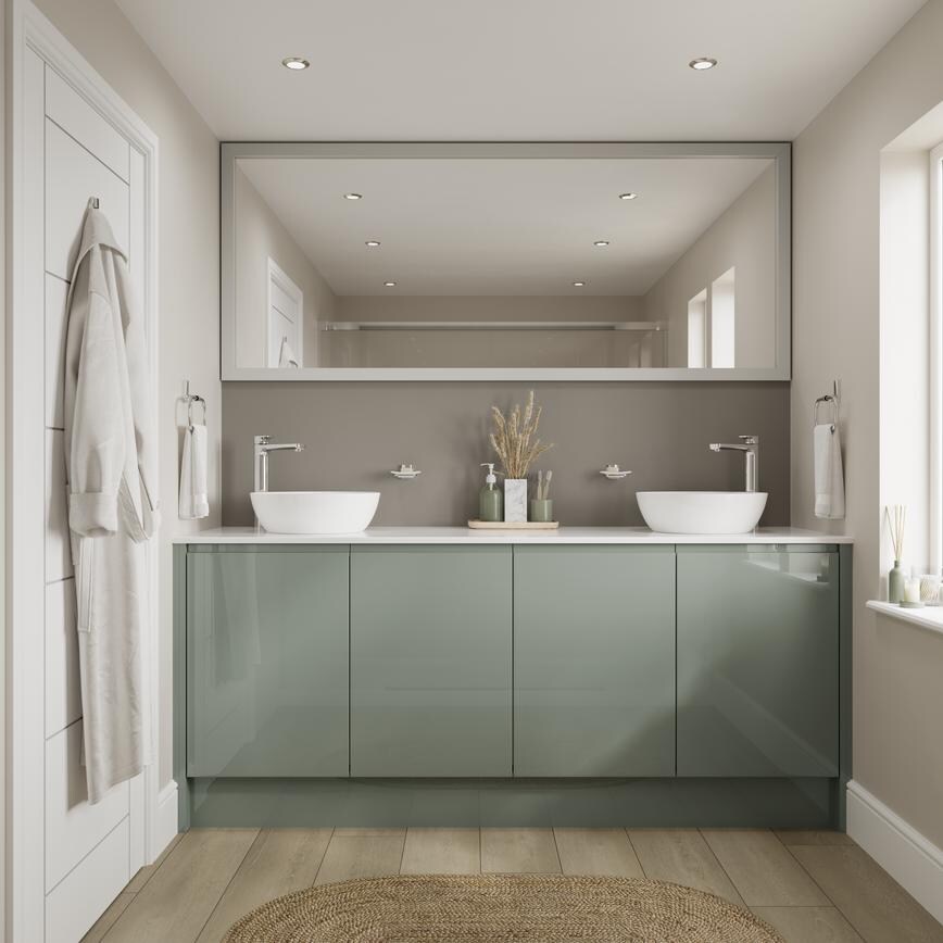 A green gloss bathroom, with slab fronts and integrated handles. It is finished with a white worktop, wall mirror, and sinks
