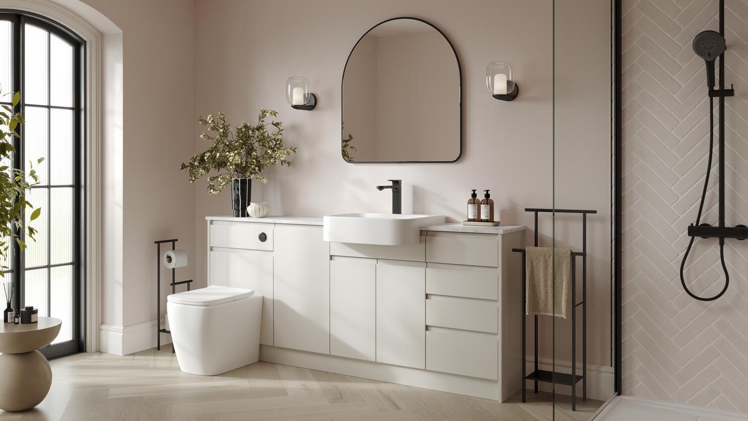 A white bathroom with porcelain-toned cabinets. It has herringbone oak flooring, glass shower panels, and black fixtures. 