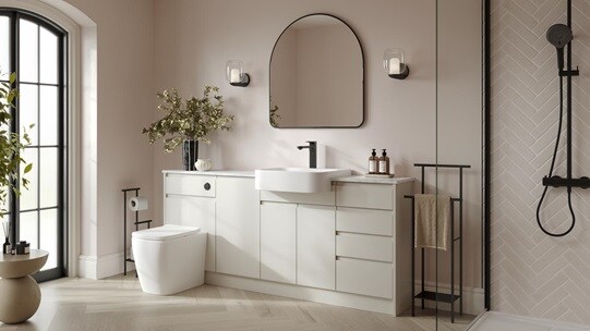 A white bathroom with porcelain-toned cabinets. It has herringbone oak flooring, glass shower panels, and black fixtures. 