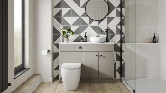 A gloss, sand grey bathroom with black fittings. There is a floor-to-ceiling glass shower enclosure and oak flooring. 